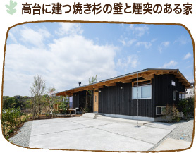 施工実績　高台に建つ焼き杉の壁と煙突のある家